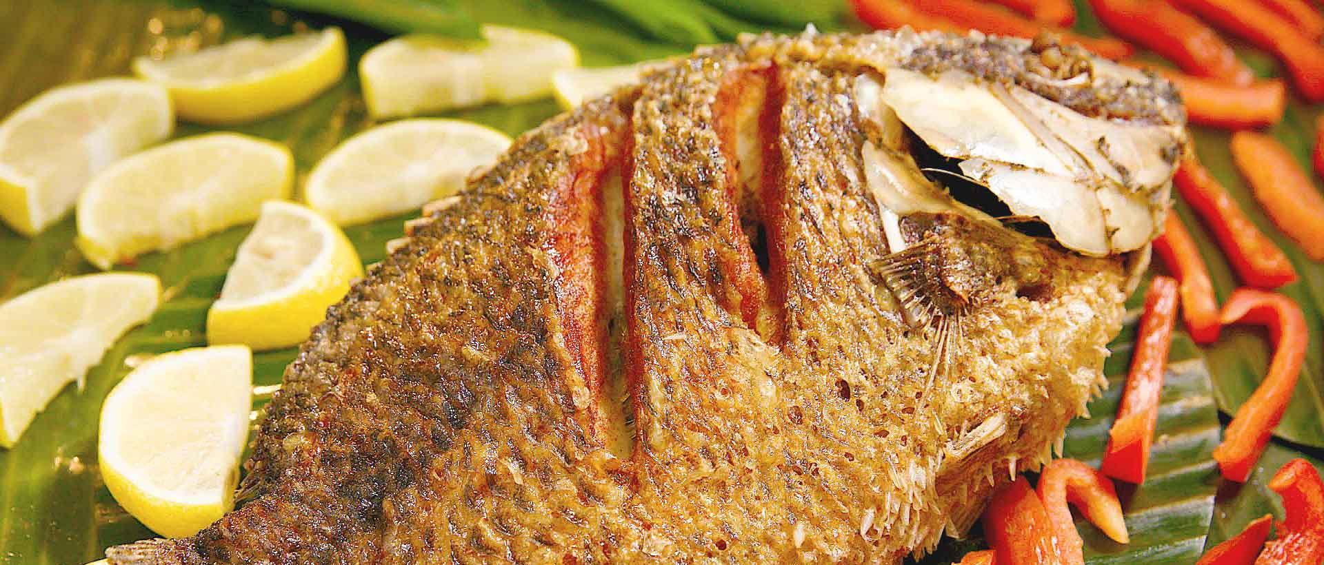 Whole fried tilapia served with vegetables at House of Grill
